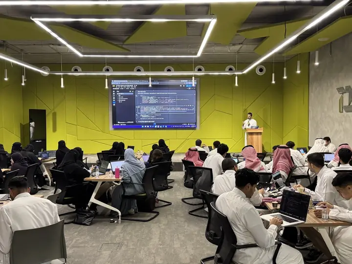 مشاركون يطبقون البرمجة على أجهزتهم خلال ورشة من ساعي